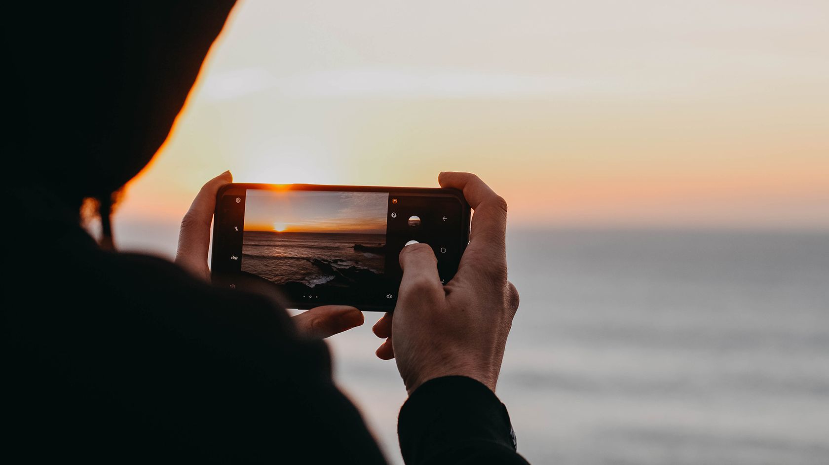 Person uses iPhone to photograph Montana de Oro coastal sunset