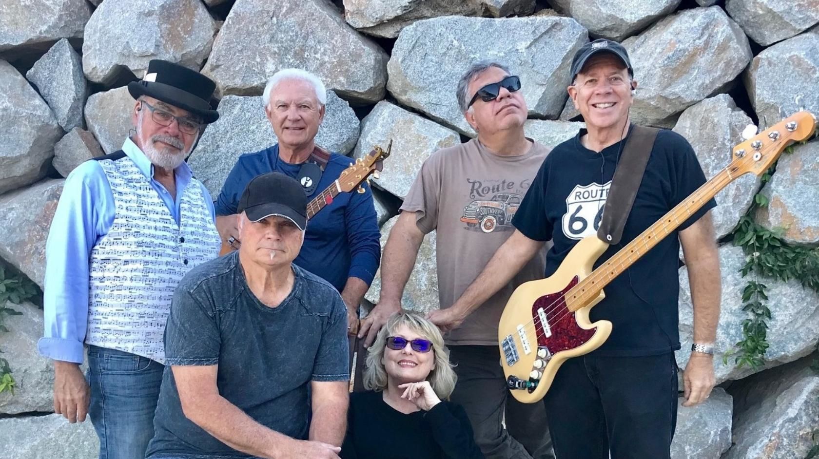 A Group Of People Standing Next To A Guitar